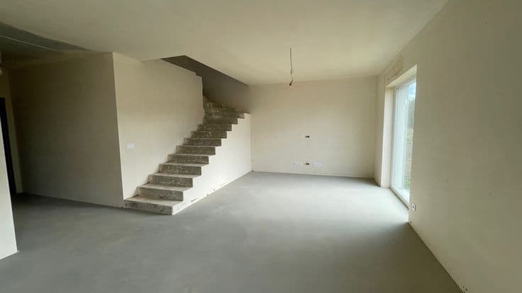Dokončené omítky v obývacím prostoru se schodištěm